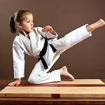 A child confidently breaking a wooden board with a taekwondo kick, showcasing focus and determination.